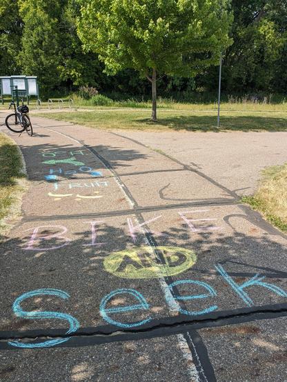 My bike next to chalk on a blacktop path that says Bike and Seek
