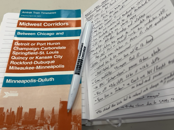 Transport Chicago notebook with Amtrak ops info written on one of the pages. A 1977 Midwest Corridors timetable is resting on the opposite page